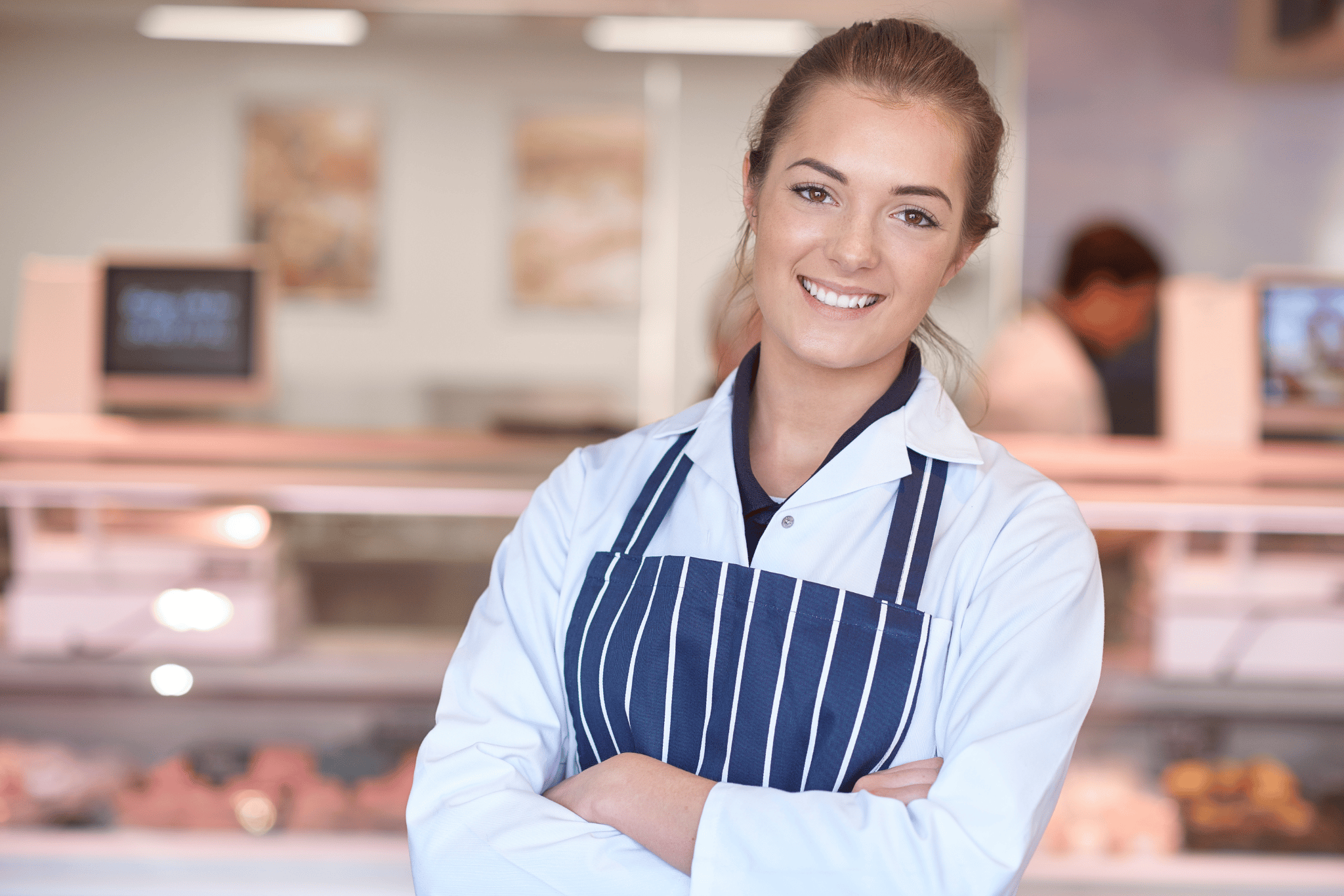 Metzgerin bei der Arbeit in der Metzgerei vor der Fleischtheke